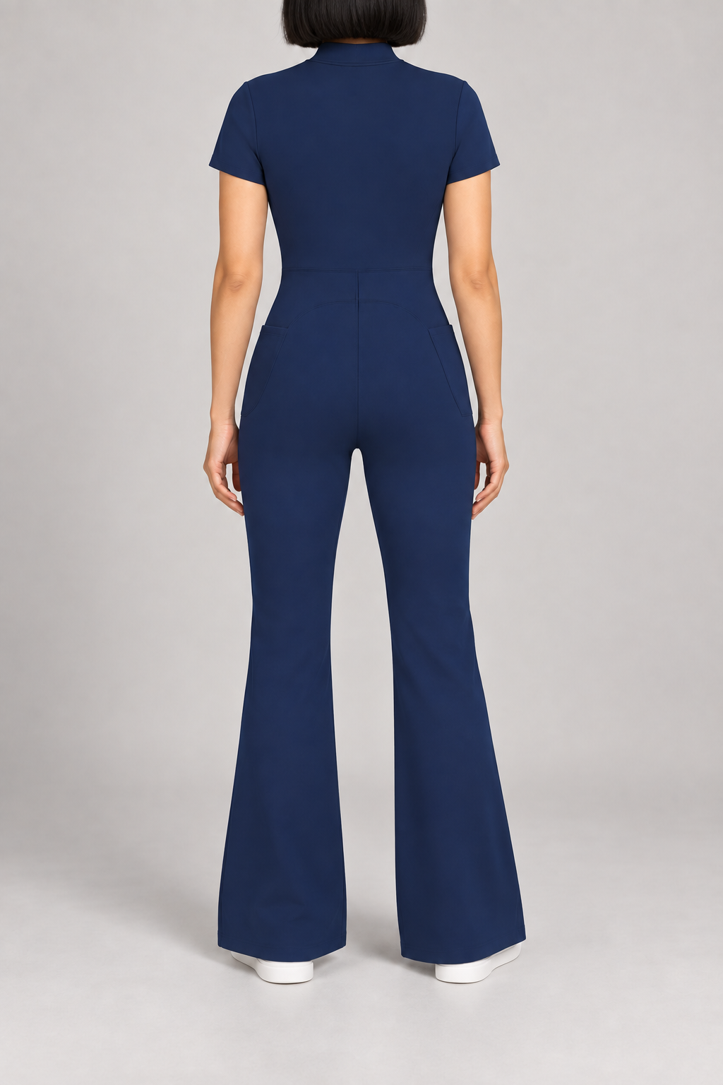 Contour Flare Zip Jumpsuit in Royal Blue. Rear studio view showing the back waist seam and curved shaping above the flared legs.