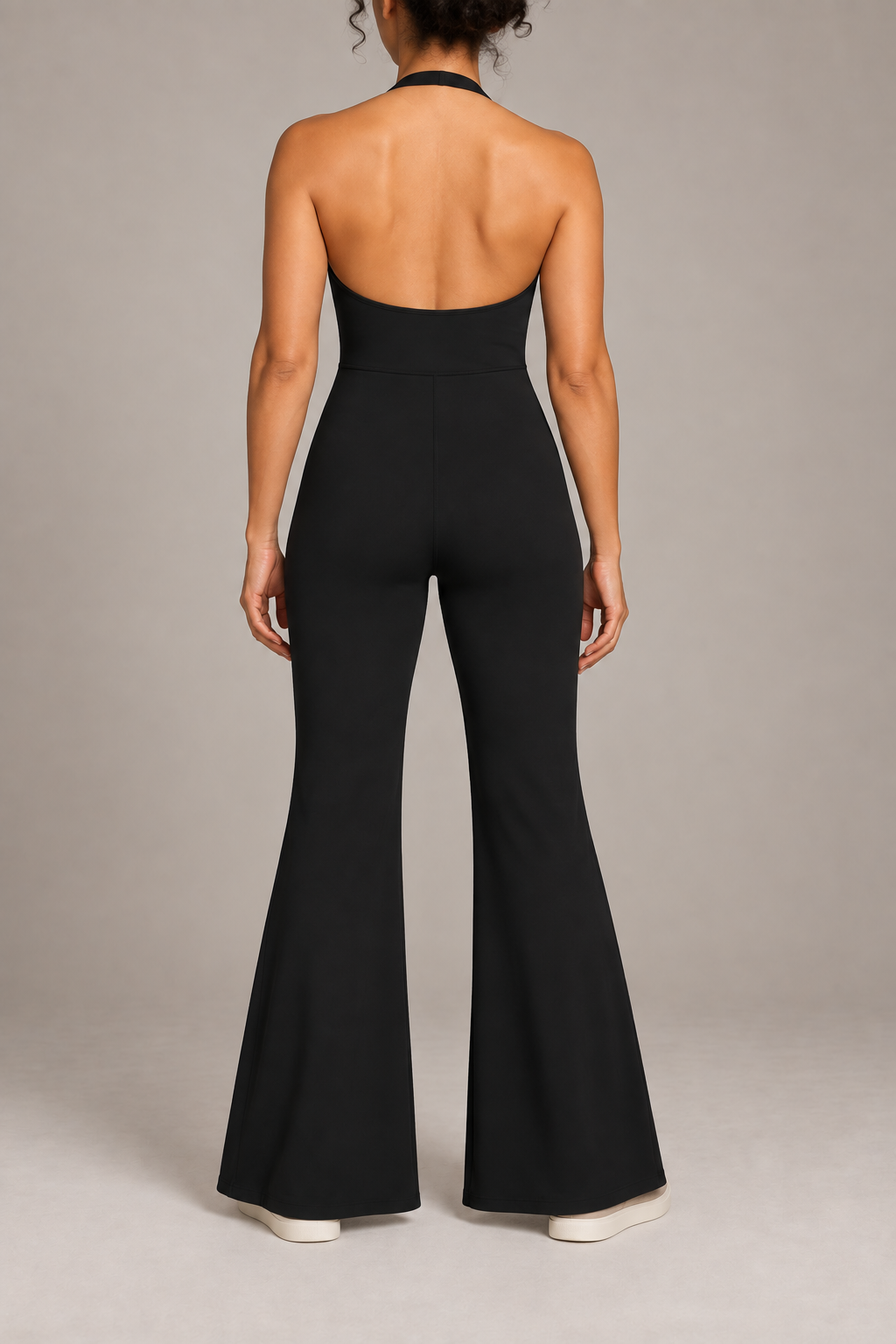 Open Line Halter Jumpsuit in Black. Rear studio view showing the open upper back, halter neck strap and defined waist seam.