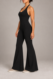 Open Line Halter Jumpsuit in Black. Three-quarter side studio view showing the sleeveless shape, waist seam and flared leg.