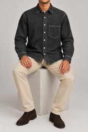 Seated view of Worn Line Denim Shirt in Black, showing the loose plain silhouette and natural denim drape.
