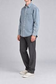 Side view of Worn Line Denim Shirt in Blue, showing the loose sleeves, curved hem and plain washed finish.