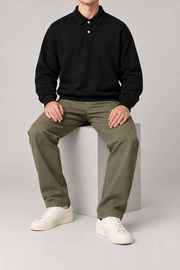 Seated view of Quiet Club Polo Sweatshirt in Black, showing its loose plain silhouette and natural fabric drape.
