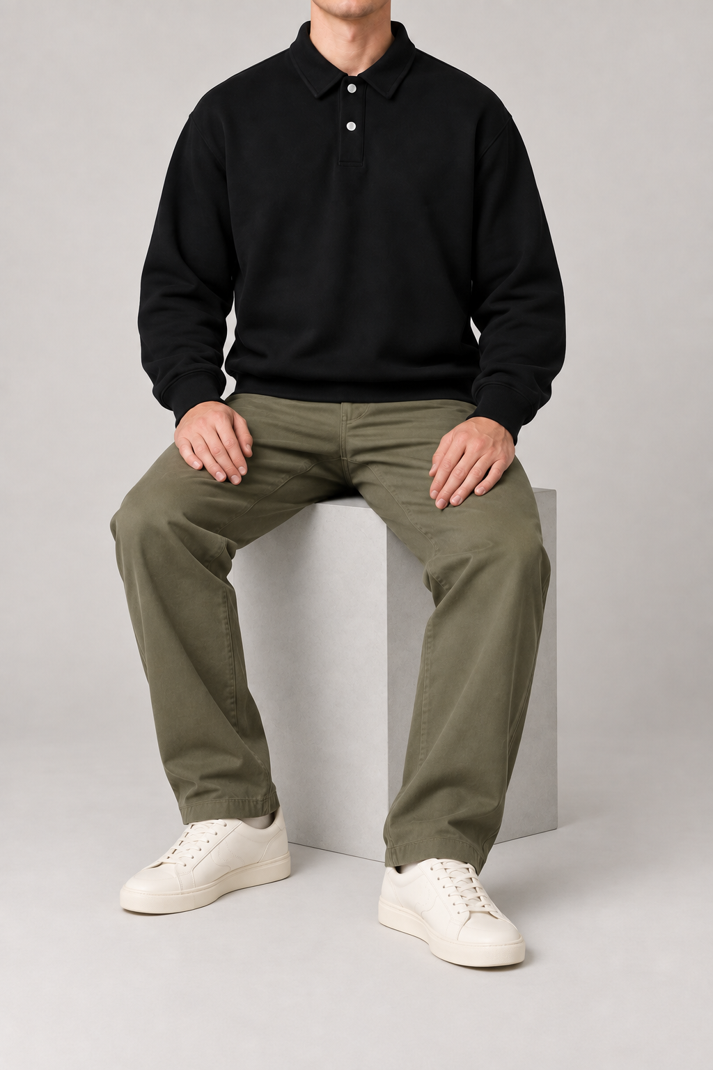 Seated view of Quiet Club Polo Sweatshirt in Black, showing its loose plain silhouette and natural fabric drape.