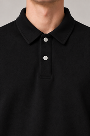 Close detail of Quiet Club Polo Sweatshirt in Black, showing the polo collar, two pale buttons and soft fabric texture.