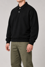 Three-quarter view of Quiet Club Polo Sweatshirt in Black, showing the long sleeves, ribbed edges and plain relaxed shape.