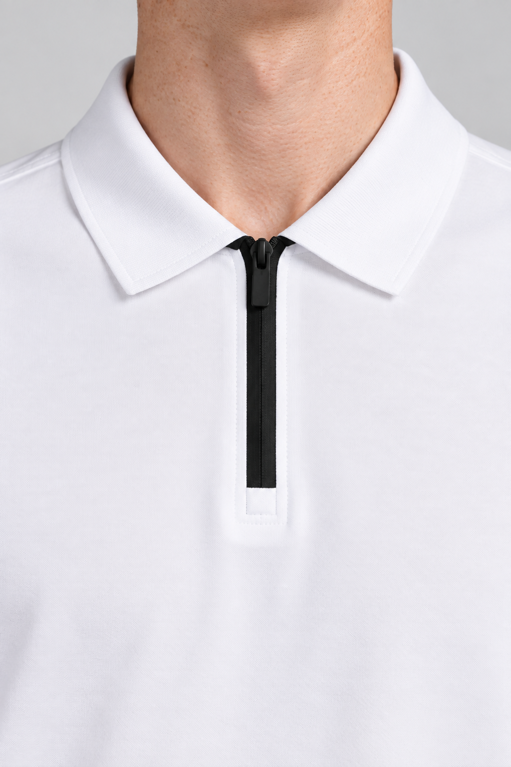 Clean Interval Zip Polo in White. Close-up showing the pointed white collar and black zipper.