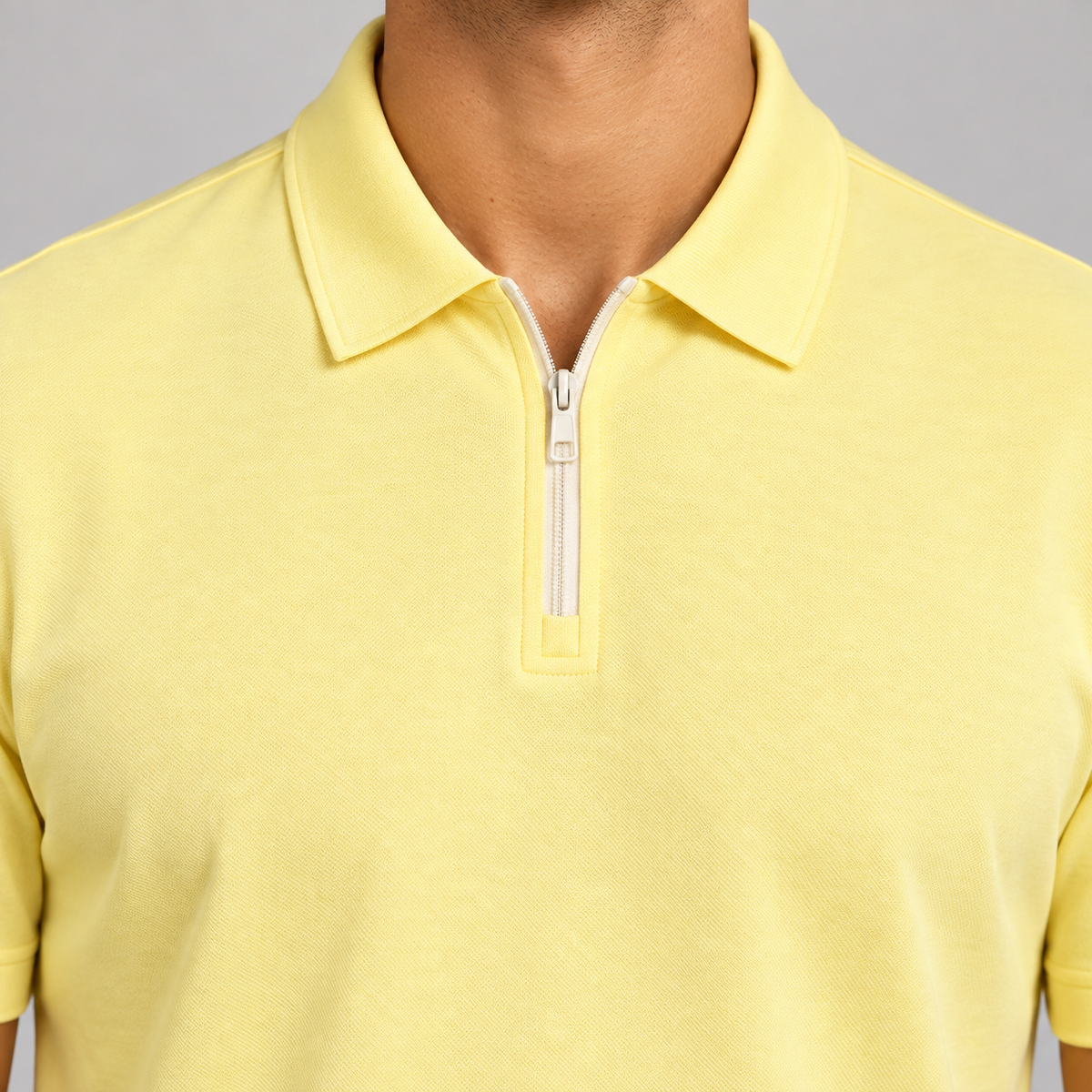 Clean Interval Zip Polo in Light Yellow. Close-up of the pointed collar and pale ivory zipper.