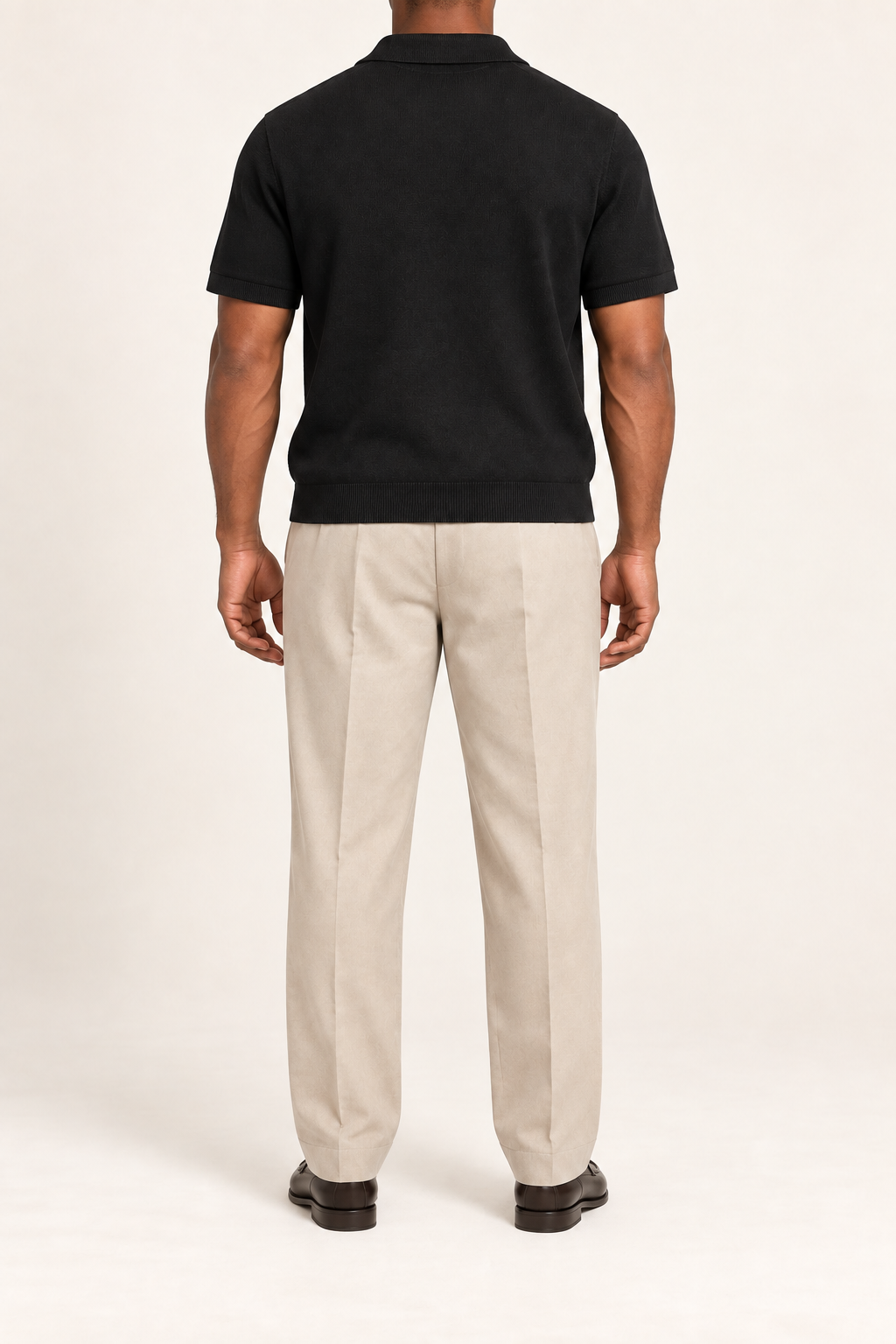 Still Hour Knit Polo in Black. Rear view showing the plain back and ribbed hem.