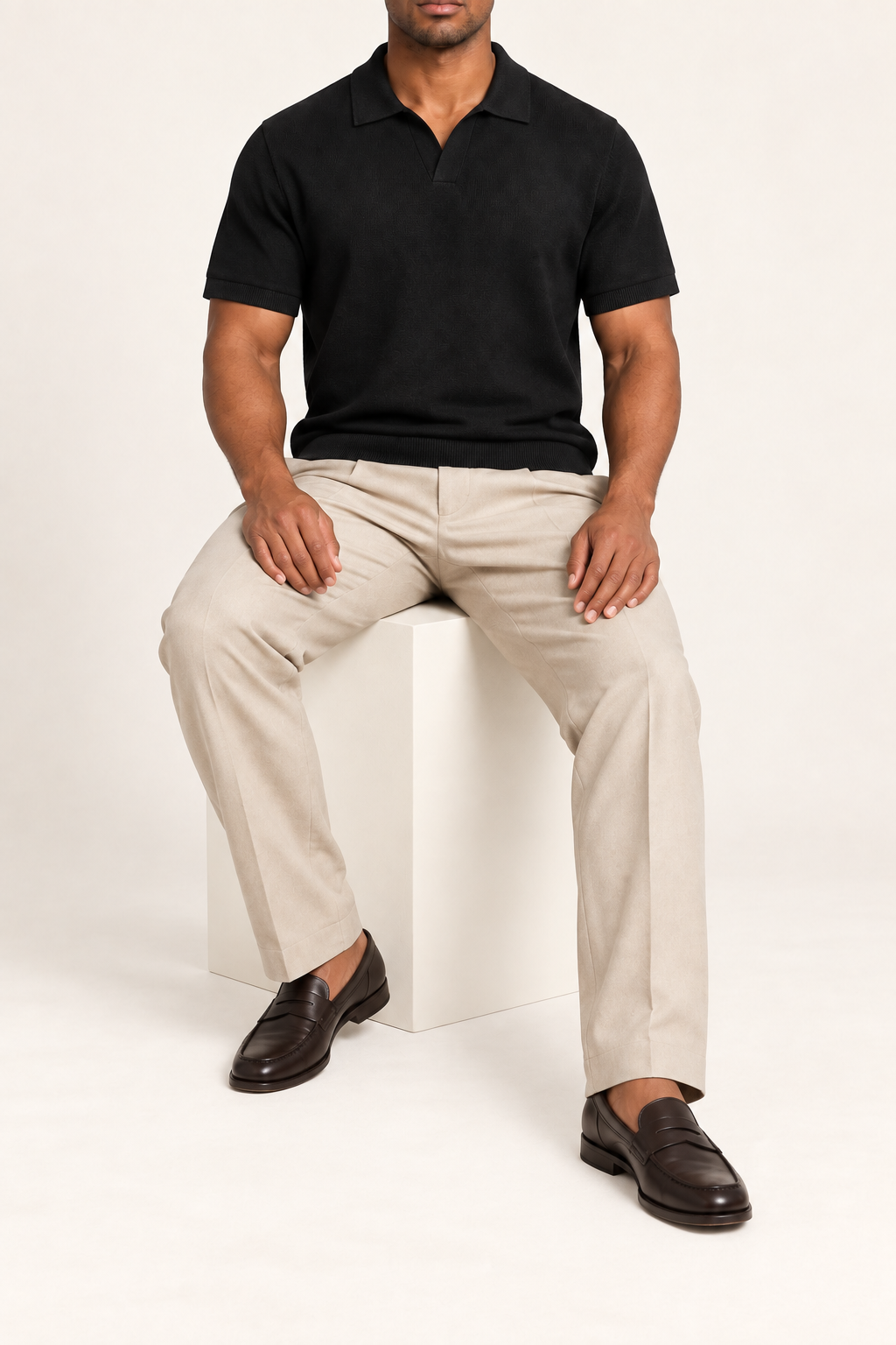 Still Hour Knit Polo in Black. Seated view showing the loose fit and substantial knit drape.