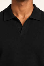 Still Hour Knit Polo in Black. Close-up of the ribbed collar and buttonless open neckline.