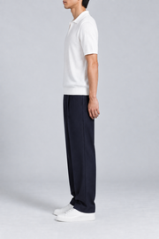 Still Hour Knit Polo in White. Side view showing the short sleeves and ribbed hem.