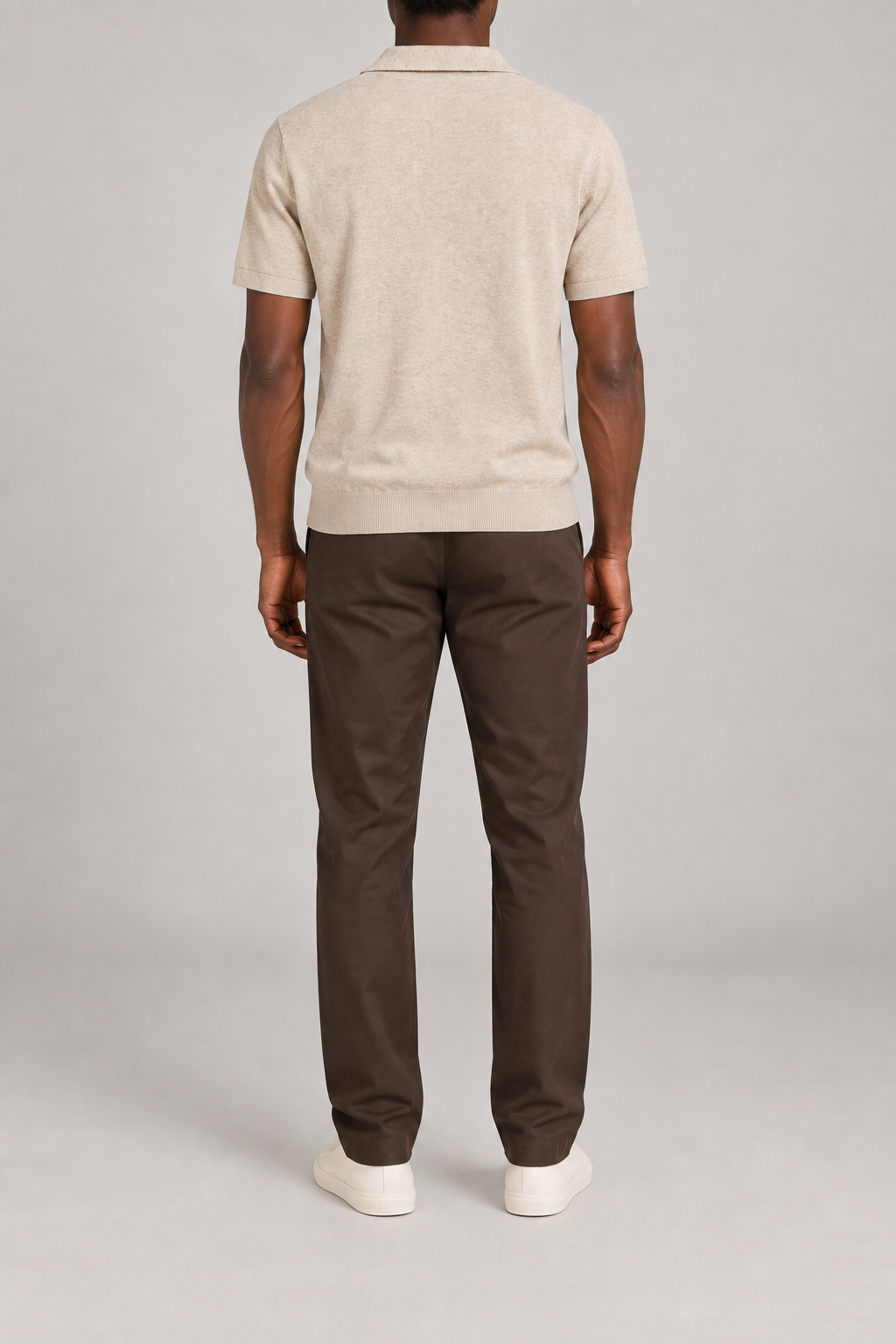 Still Hour Knit Polo in Mild Apricot. Rear view showing the plain back and ribbed hem.
