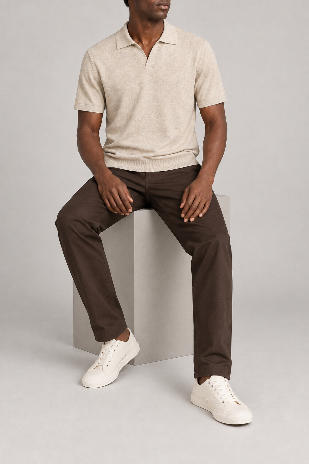 Still Hour Knit Polo in Mild Apricot. Seated view showing the loose fit and knit drape.