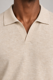 Still Hour Knit Polo in Mild Apricot. Close-up showing the fine heathered knit and buttonless neckline.