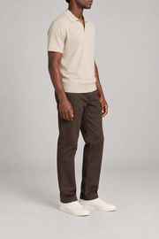 Still Hour Knit Polo in Mild Apricot. Three-quarter side view showing the short sleeves and ribbed hem.