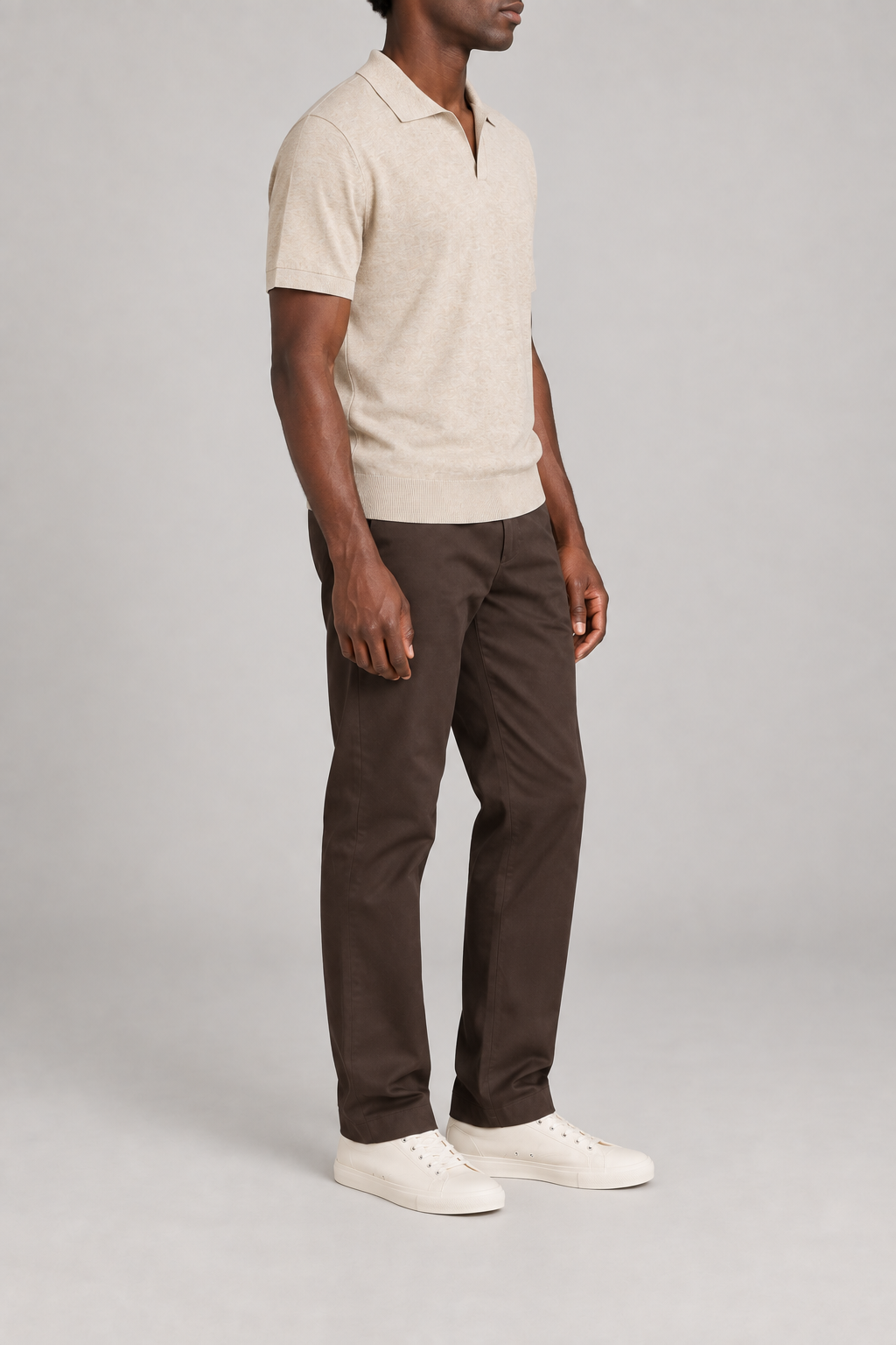 Still Hour Knit Polo in Mild Apricot. Three-quarter side view showing the short sleeves and ribbed hem.