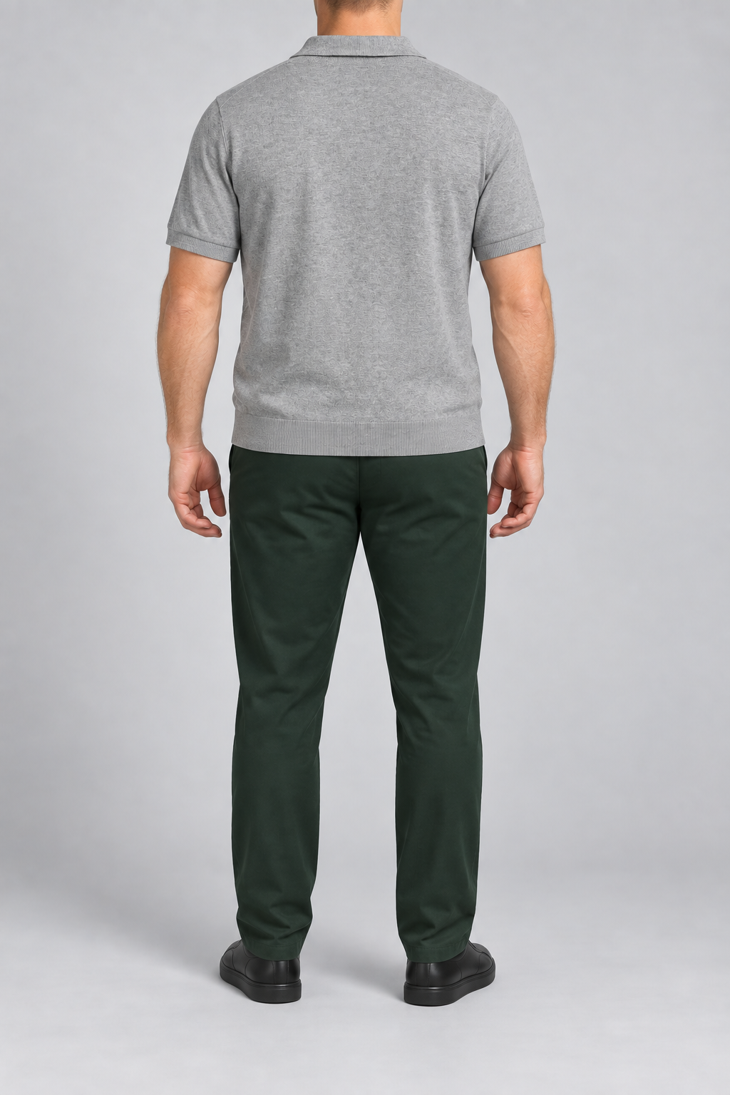 Rear studio view showing the plain back and ribbed hem of Still Hour Knit Polo in Flower Gray.