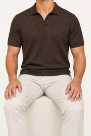 Seated studio view showing the relaxed drape and ribbed hem of Still Hour Knit Polo in Dark Brown.