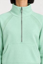 Close-up studio view showing the high collar, silver-tone zip and ribbed shoulder inserts of Curve Interval Half-Zip Sweatshirt in Green.