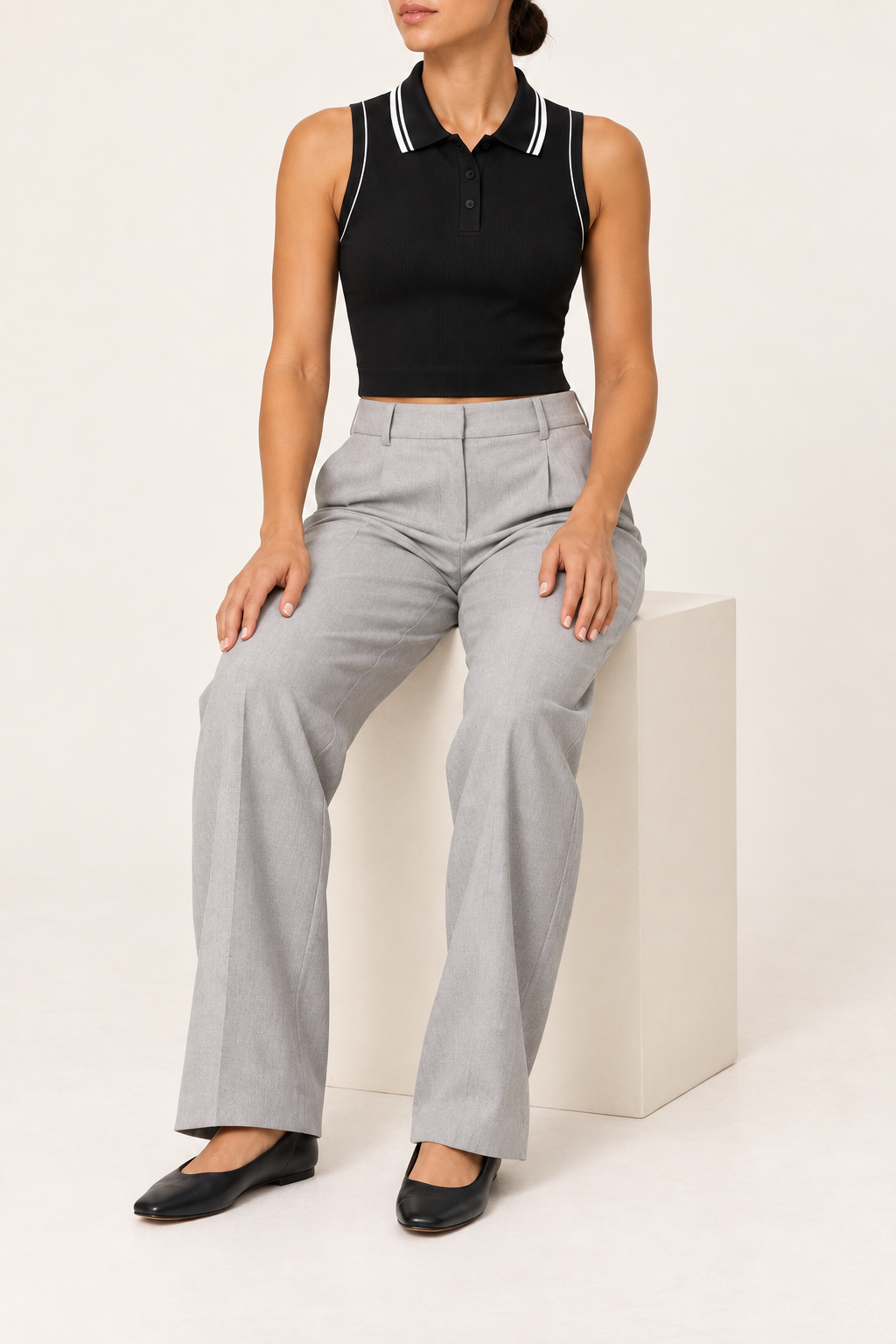 Seated studio view showing the close cropped fit and sleeveless shape of Court Line Polo Tank in Black with White.