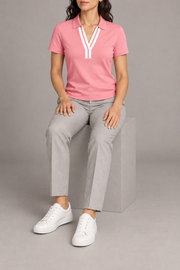 Court Ease V-Neck Polo in Pink. Seated studio view showing the pink polo's natural drape.
