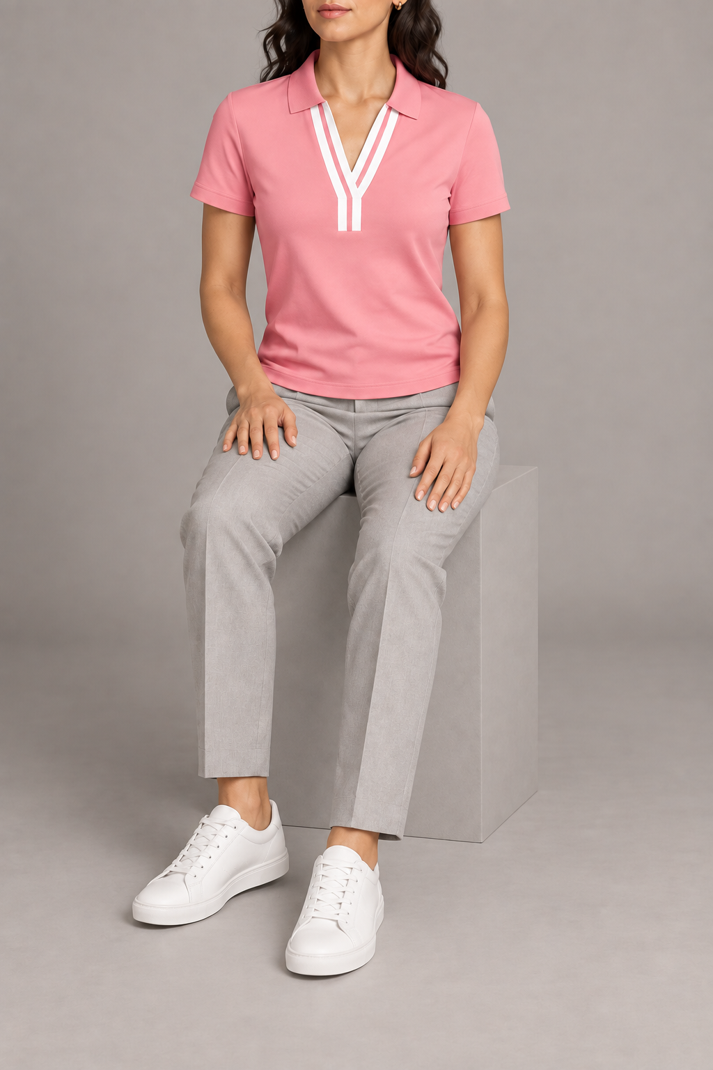 Court Ease V-Neck Polo in Pink. Seated studio view showing the pink polo's natural drape.