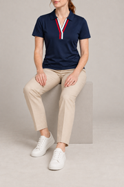 Court Ease V-Neck Polo in Navy Blue. Seated studio view showing the navy polo's natural drape.