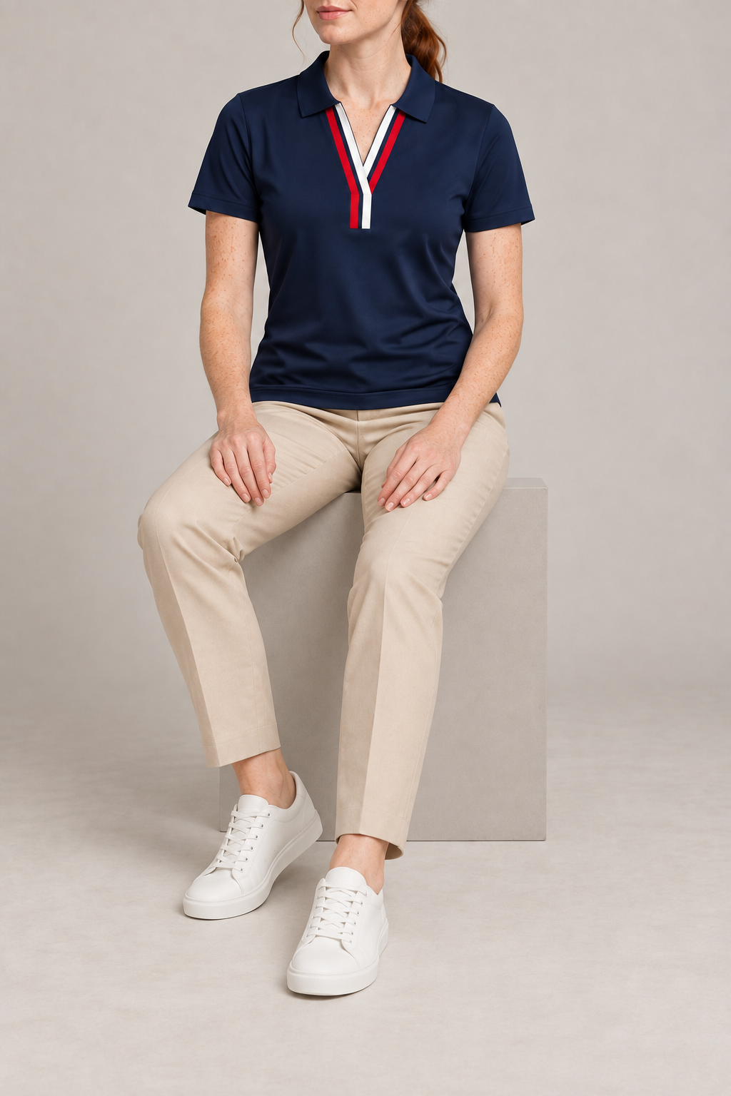 Court Ease V-Neck Polo in Navy Blue. Seated studio view showing the navy polo's natural drape.