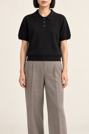 Soft Poise Knit Polo in Black. Front studio view showing the short boxy shape and three-button placket.
