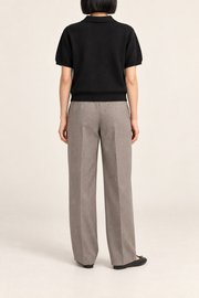 Soft Poise Knit Polo in Black. Rear studio view showing the plain black knit and ribbed hem.