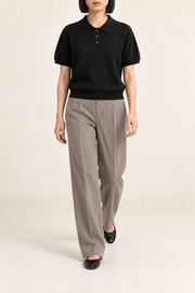 Soft Poise Knit Polo in Black. Walking studio view showing the black polo's relaxed drape.