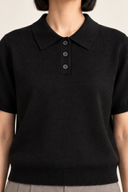Soft Poise Knit Polo in Black. Close-up showing the black ribbed collar and three dark buttons.