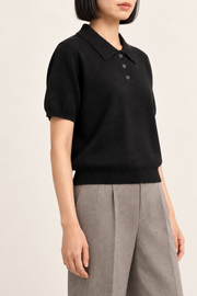 Soft Poise Knit Polo in Black. Three-quarter studio view showing short sleeves and ribbed cuffs and hem.