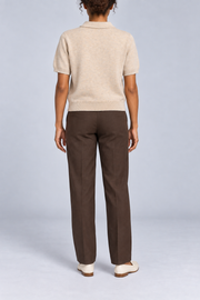 Soft Poise Knit Polo in Apricot. Rear studio view showing the plain apricot knit and ribbed hem.