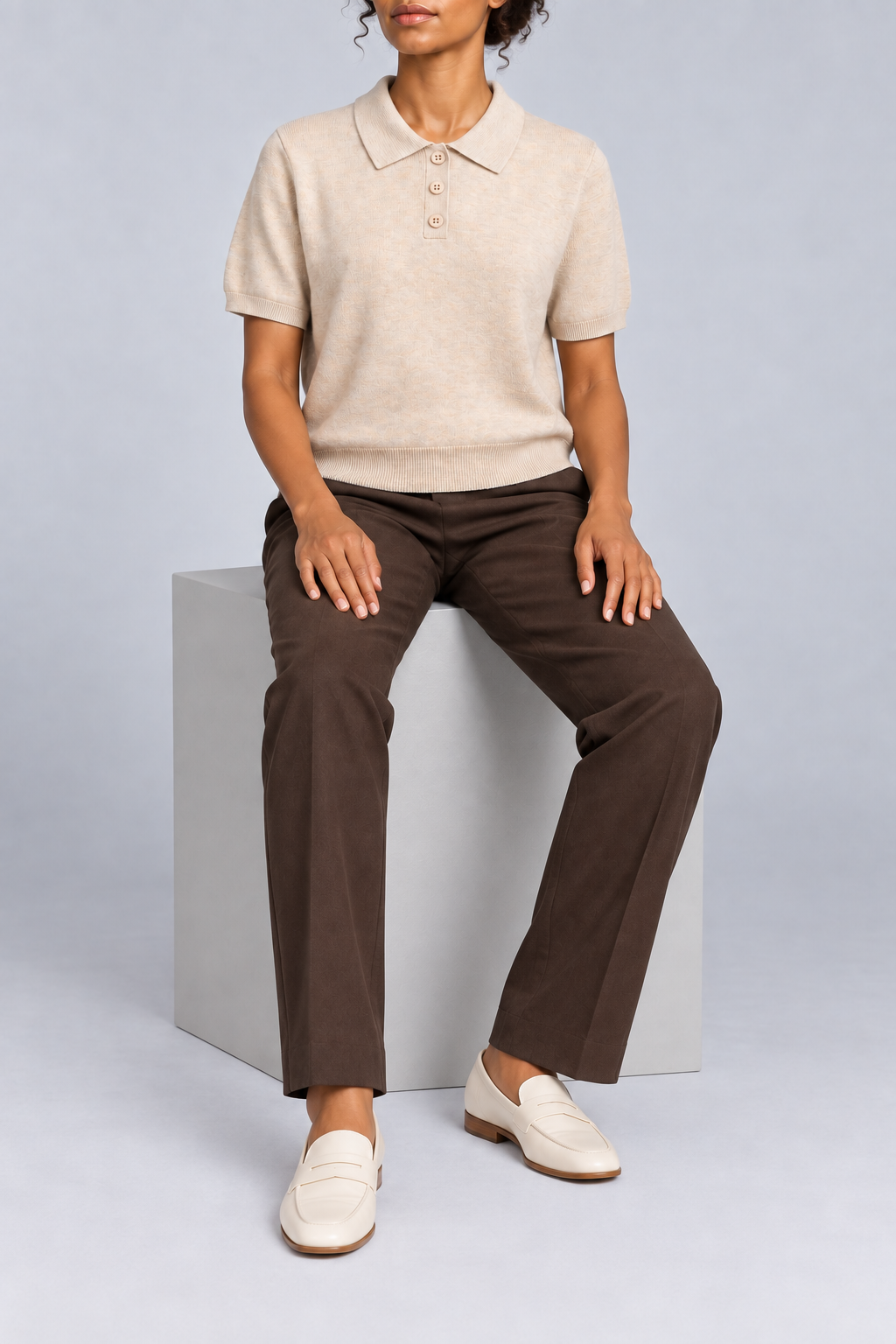Soft Poise Knit Polo in Apricot. Seated studio view showing the apricot polo's relaxed drape.