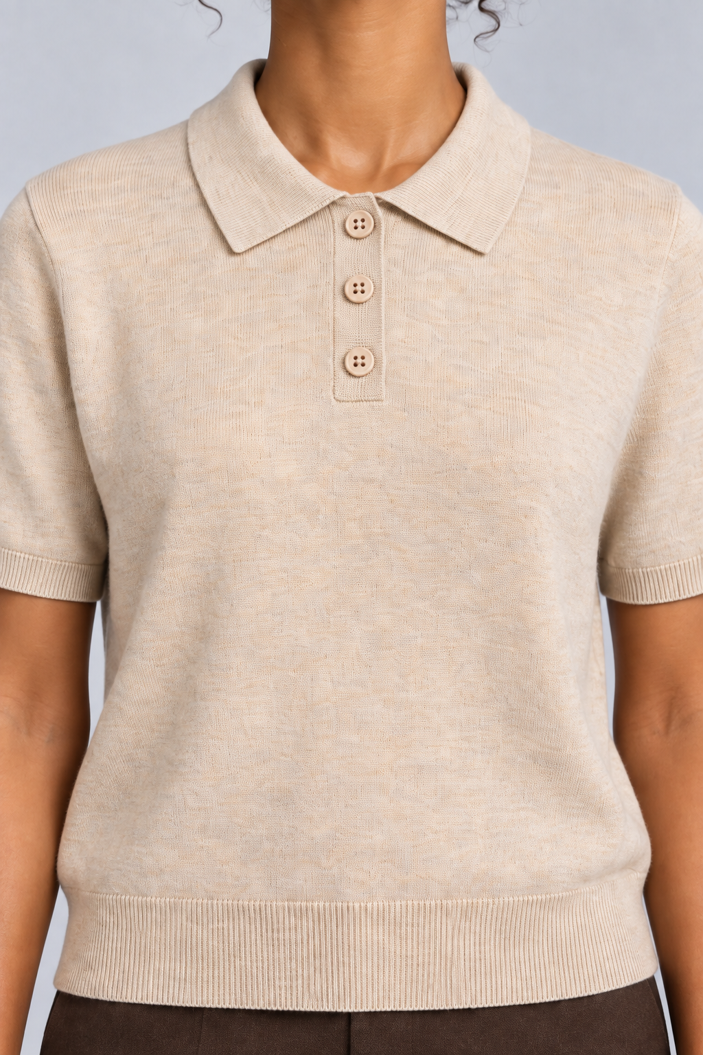 Soft Poise Knit Polo in Apricot. Close-up showing the apricot ribbed collar and three matching buttons.
