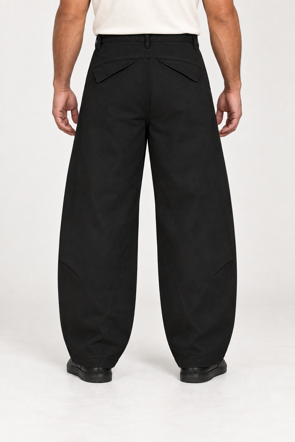 Rear studio view of Quiet Arc Barrel Pants in Black, showing angled pocket flaps and leg shaping.