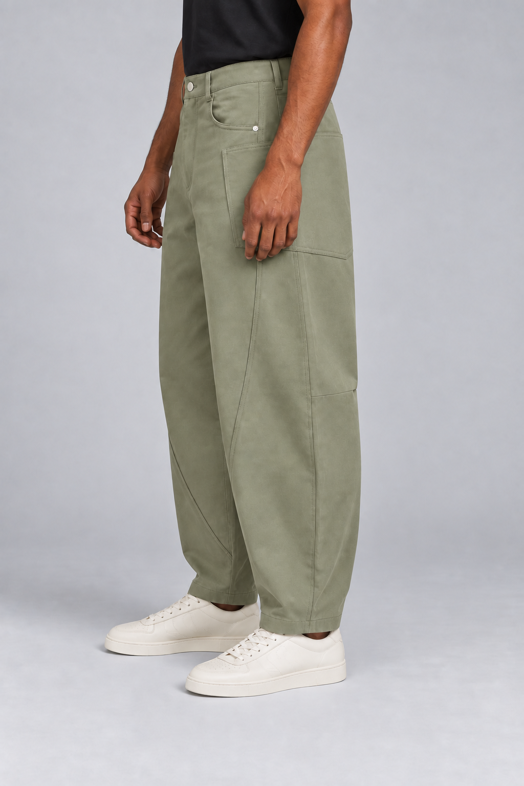 Side studio view of Field Arc Barrel Pants in Gray Green, showing the wraparound patch pocket and curved leg.
