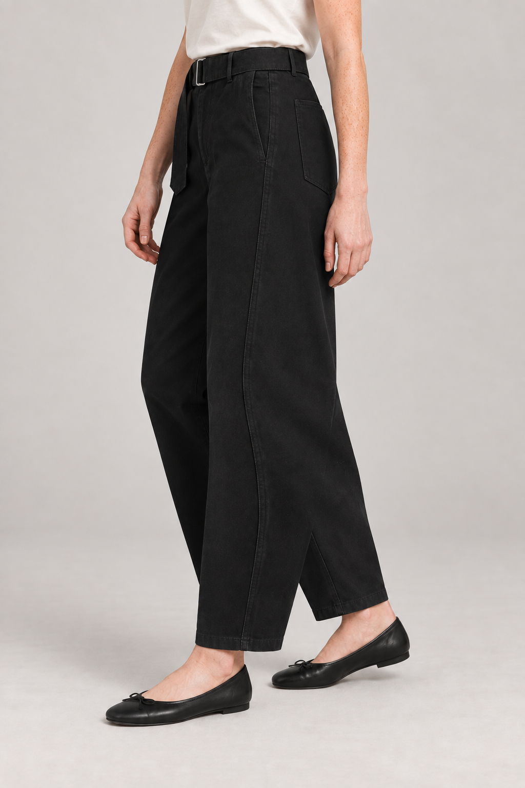 Three-quarter side studio view of Soft Arc Belted Chinos in Black, showing twisted seams and the metal belt buckle.