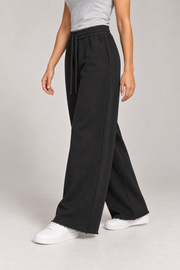 Side studio view of Soft Pause Wide Leg Sweatpants in Black, showing the side pocket and raw-edge finish.