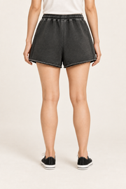 Rear studio view of Faded Hours Raw Edge Shorts in Black, showing the plain back, relaxed shape and raw hems.