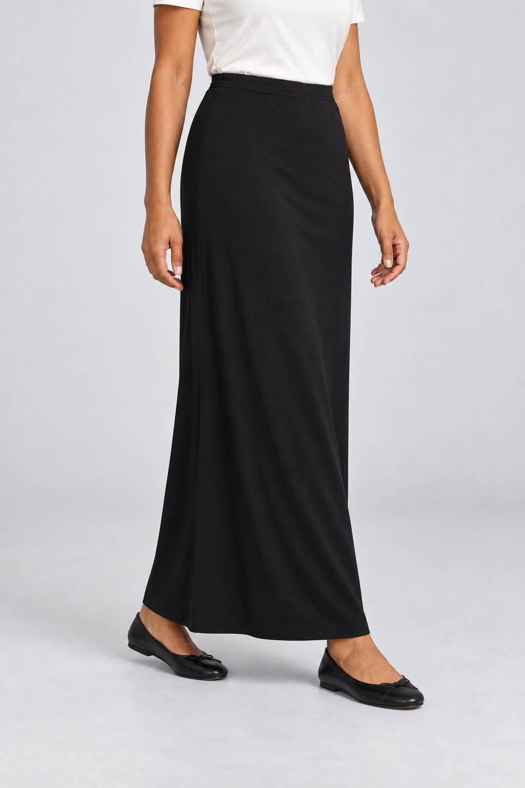 Three-quarter studio view of Quiet Column Knit Maxi Skirt in Black, showing the long hem and fluid fabric during a natural step.