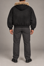 Rear view of Dusk Shelter Boxy Zip Hoodie in Black showing the fur-trimmed hood, curved back seam and ribbed hem.
