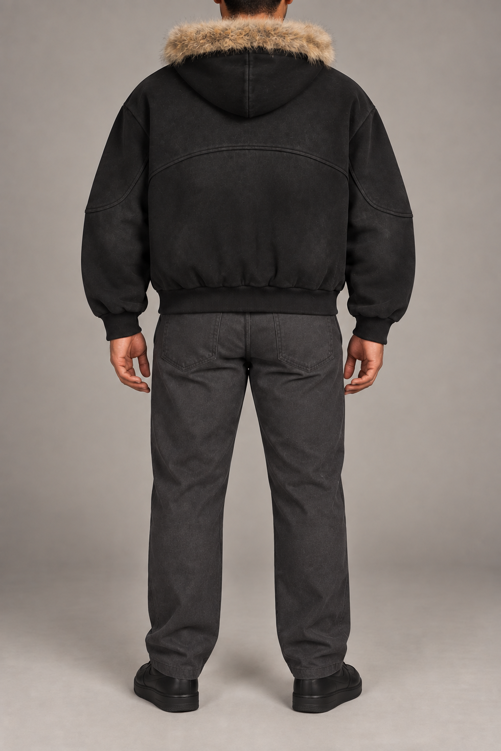 Rear view of Dusk Shelter Boxy Zip Hoodie in Black showing the fur-trimmed hood, curved back seam and ribbed hem.
