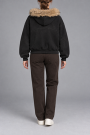 Rear view of Night Shelter Boxy Zip Hoodie in Black showing the fur-trimmed hood, curved back seam and ribbed hem.
