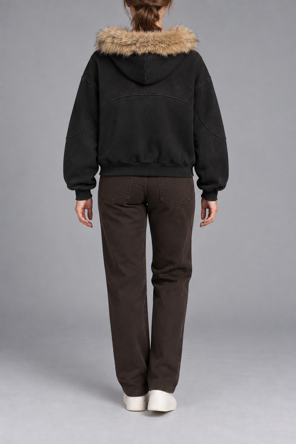 Rear view of Night Shelter Boxy Zip Hoodie in Black showing the fur-trimmed hood, curved back seam and ribbed hem.