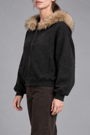 Three-quarter view of Night Shelter Boxy Zip Hoodie in Black showing its oversized sleeves, front pocket and washed finish.