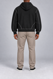Rear view of Outline Studio Fleece Zip Hoodie in Black showing the plain hood and diagonal contrast seams near the hem.