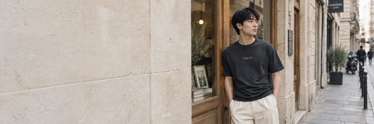 Man in a black TELLS shirt and cream trousers