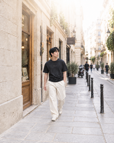 Man in a black TELLS shirt and cream trousers